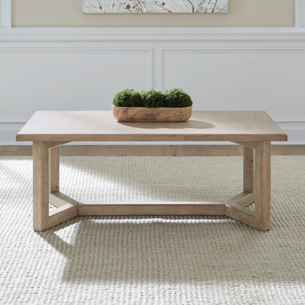 Proximity Place rectangular wooden cocktail table with moss centerpiece on a cream rug.