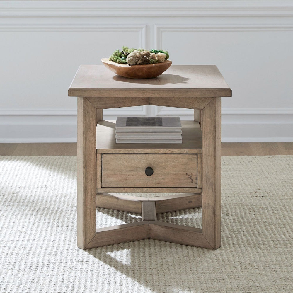 Proximity Place rectangular light wood end table with drawer and shelf on a textured rug.