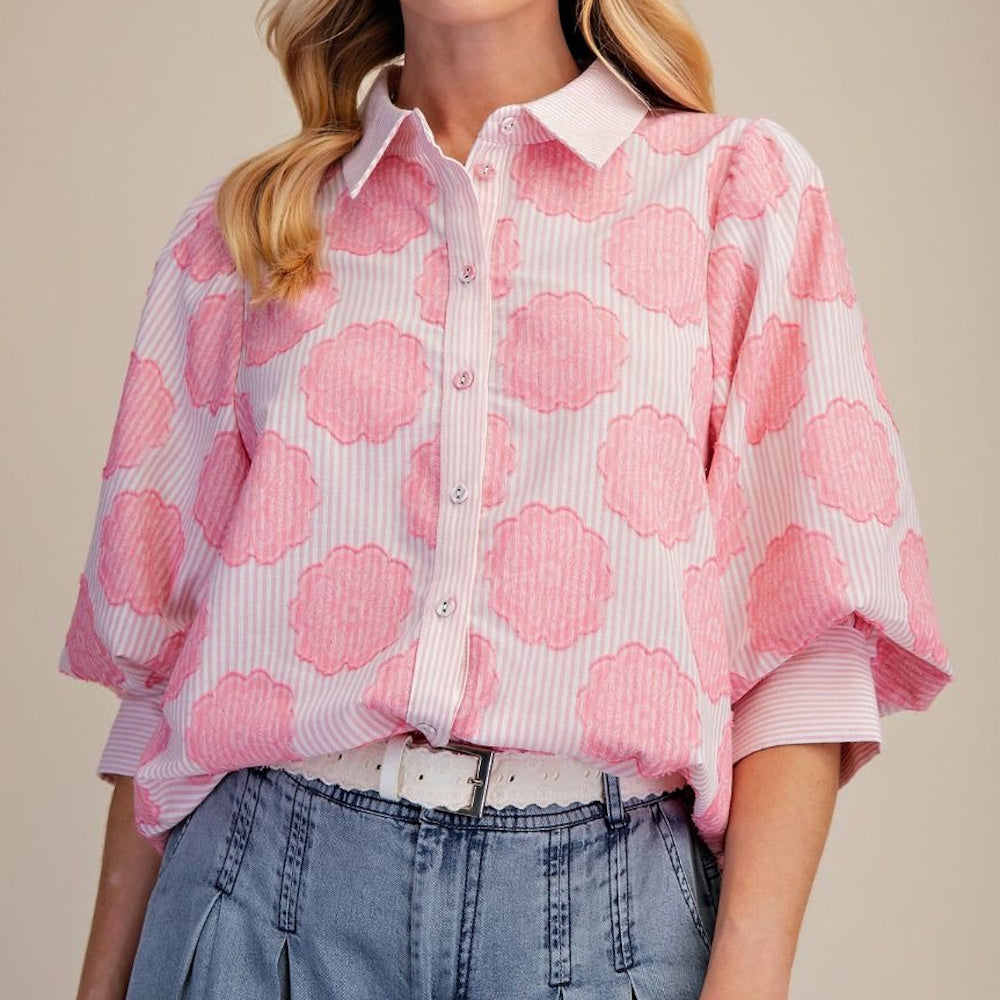 Pink puff sleeve floral and stripe button-down shirt paired with light wash denim pants and a white belt.