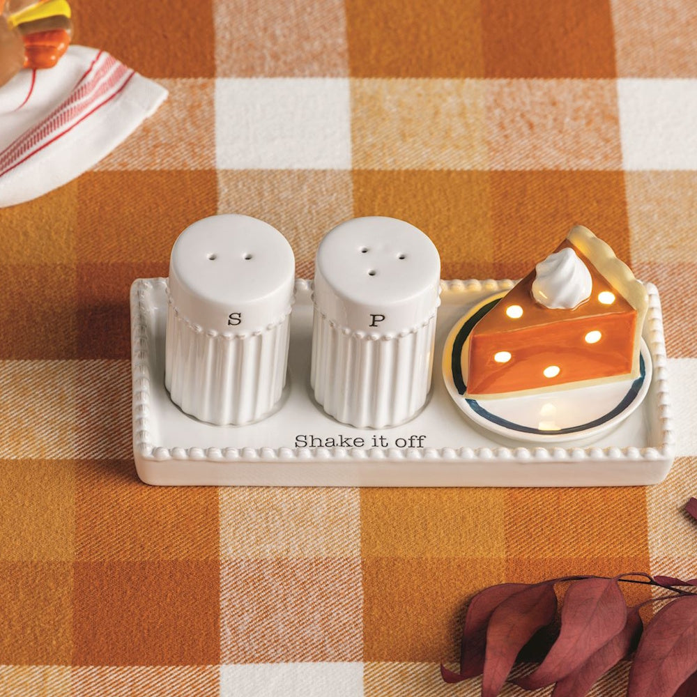 White ceramic salt and pepper shakers with a glowing pumpkin pie slice on a tray.