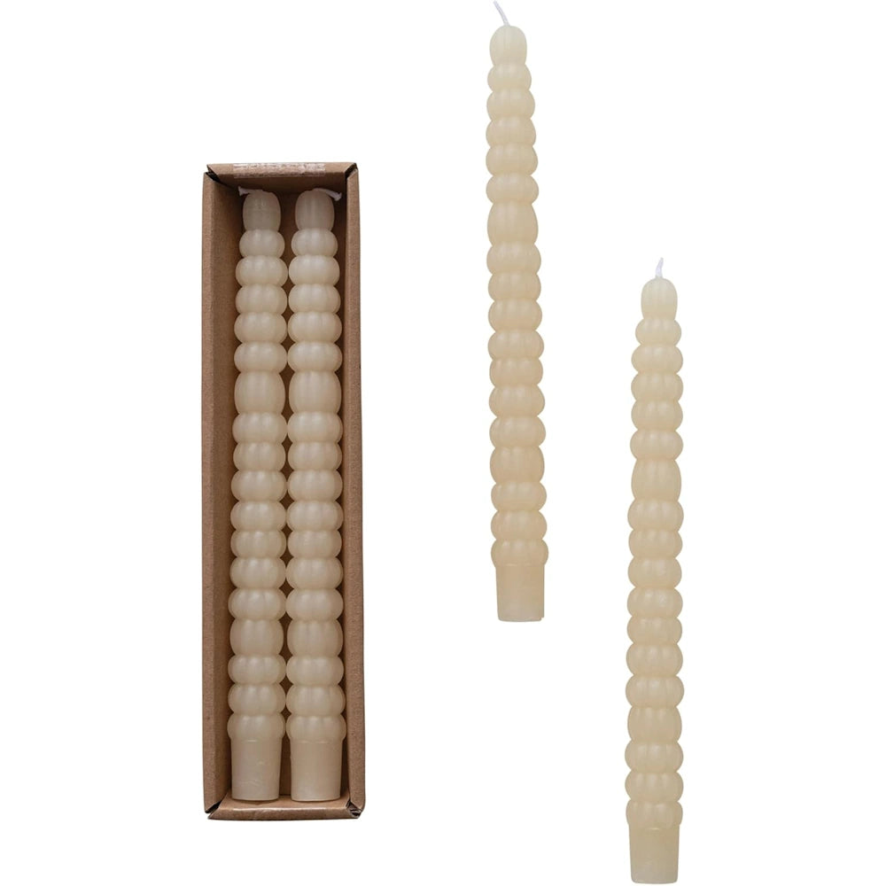Two ivory taper candles with a textured, beaded design shown next to their cardboard packaging box.