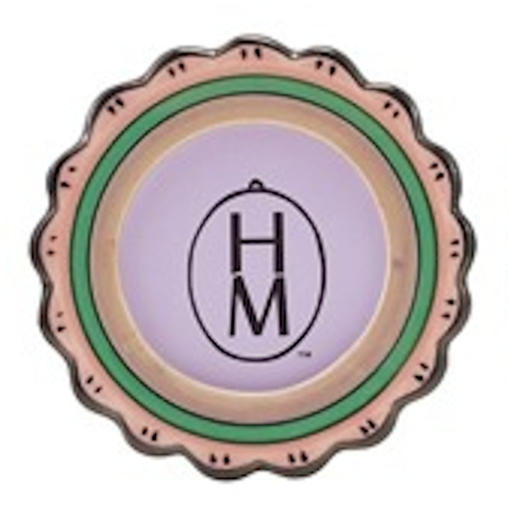 Scalloped circular magnet with pastel green and tan borders, featuring a purple center with a black "HM" logo in an oval.