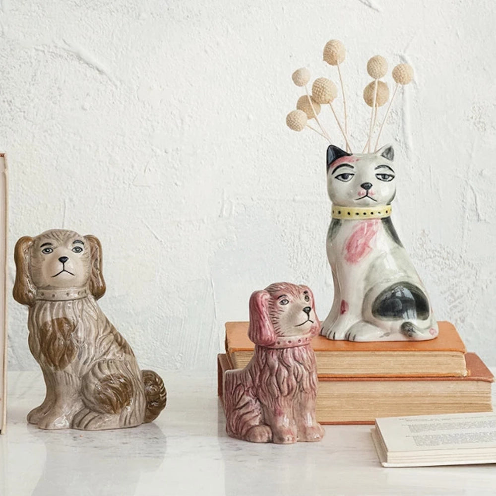 Vintage style ceramic dog figurines and hand-painted cat bud vase on a stack of old books for home shelf decor.