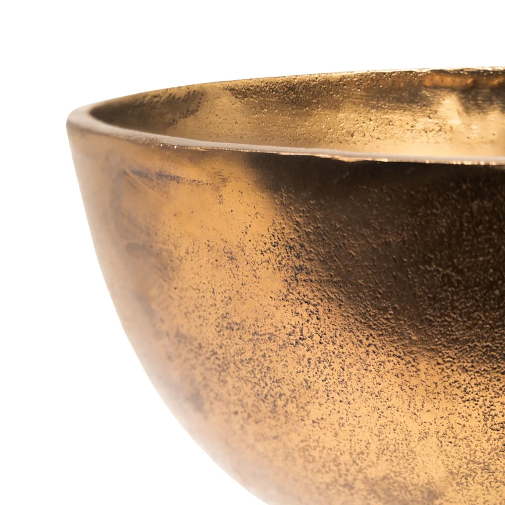 Close-up of a rustic, textured gold metal bowl showing its speckled antique finish and smooth rim.