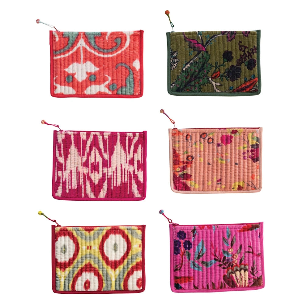 A collection of six unique, quilted velvet makeup bags on a white background, each with colorful patterns and bead charms.
