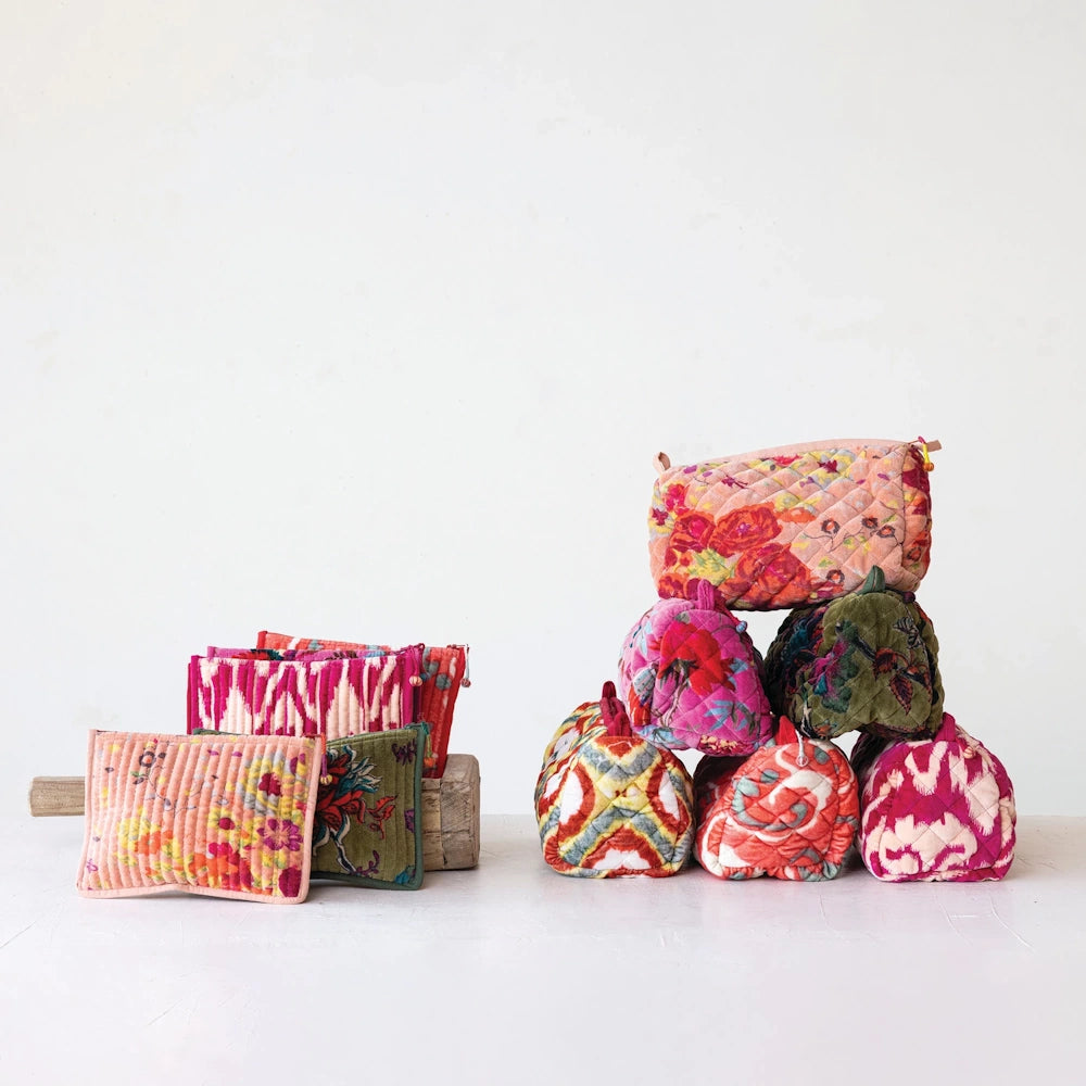 Colorful quilted velvet zip pouches in floral and ikat patterns stacked and arranged against a plain white background.