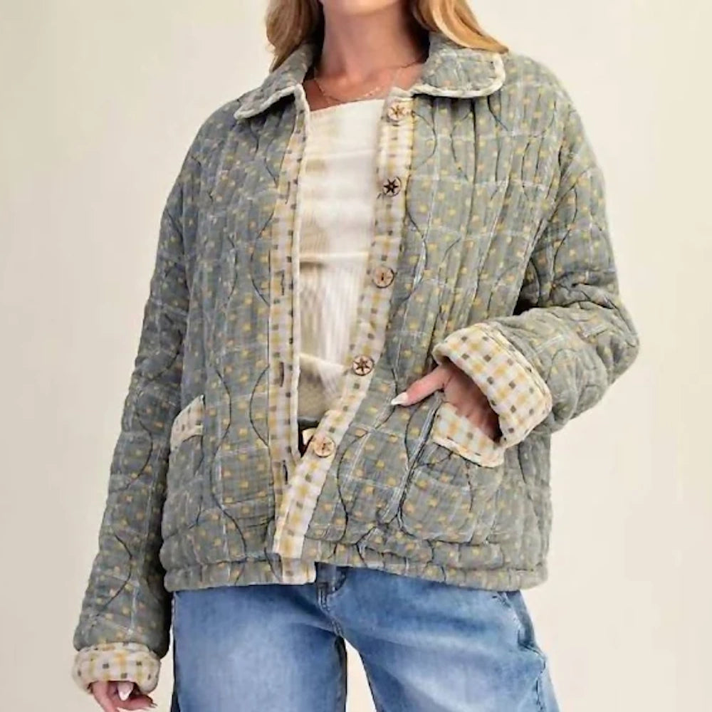 Front view of a mineral-washed green quilted jacket with plaid lining and wooden buttons worn by a model.