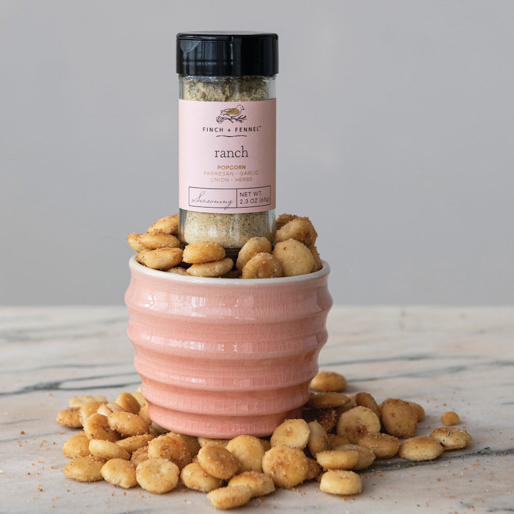 A jar of Finch + Fennel ranch seasoning nestled in a pink bowl of small, round oyster crackers.