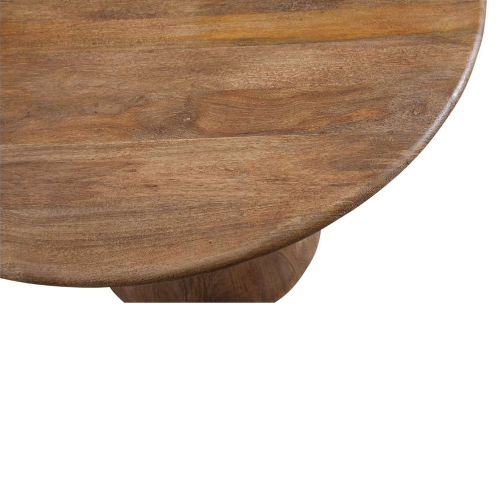 Top-down view of a round, natural brown mango wood pedestal dining table with a visible grain texture.