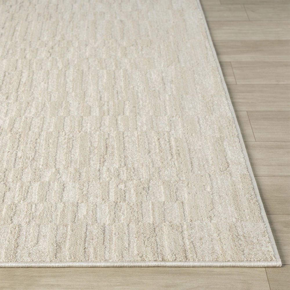 Close up of cream textured area rug with subtle geometric pattern, bound edges and low profile design.