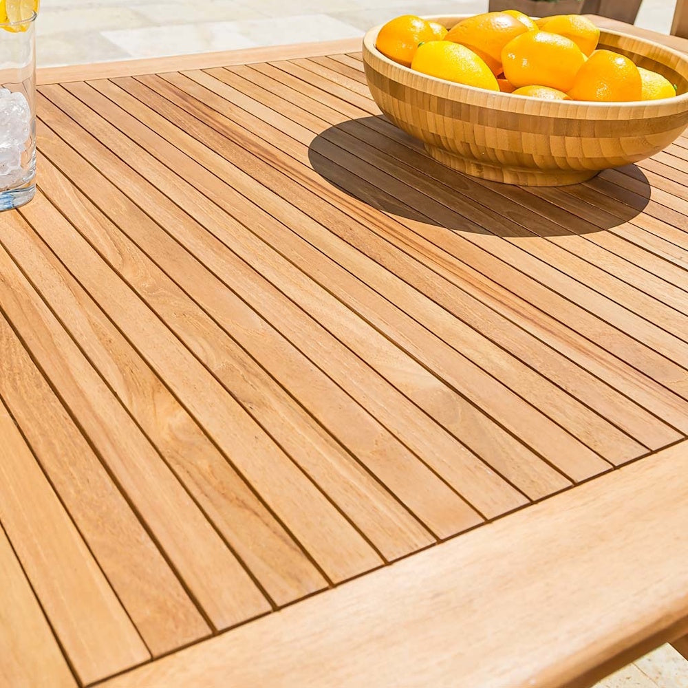 Overhead close-up of a natural slatted teak tabletop with a bowl of lemons.