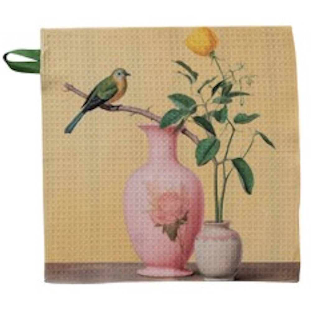 A yellow waffle-weave dish cloth featuring an illustration of a bird on a branch beside a pink floral vase.