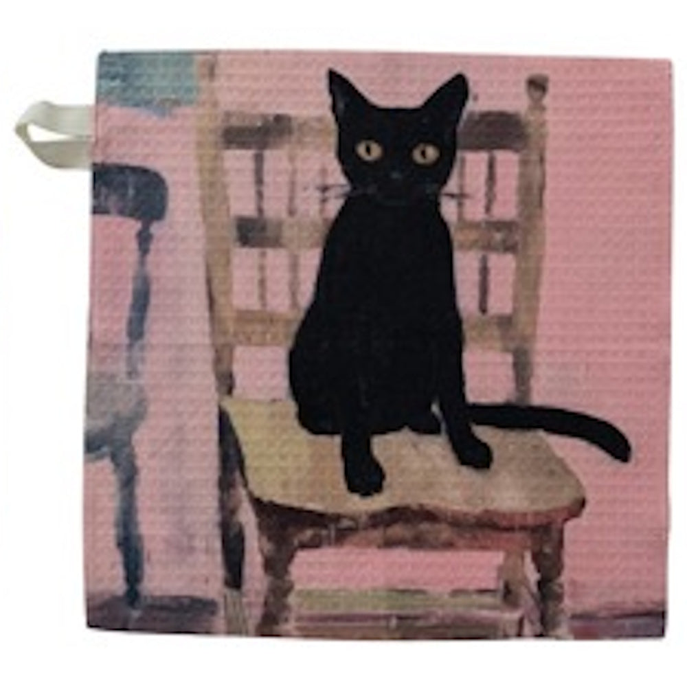 A black cat with yellow eyes sitting on a wooden chair against a pink background, printed on a textured dish cloth.