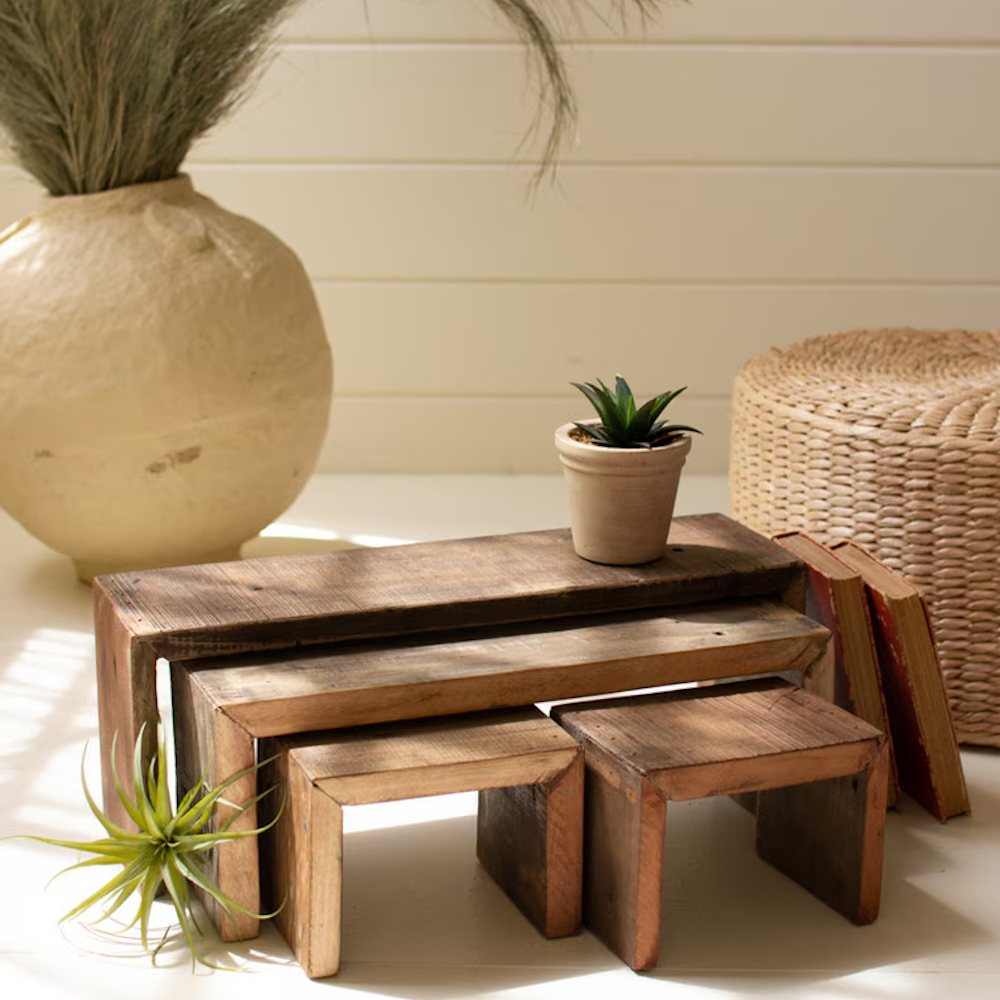 Set of rustic, recycled wood nesting risers styled with small plants, books, and home decor.