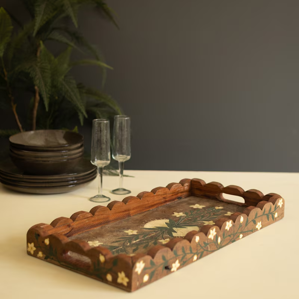 Scalloped wooden serving tray with hand-painted floral details, displayed next to glassware.