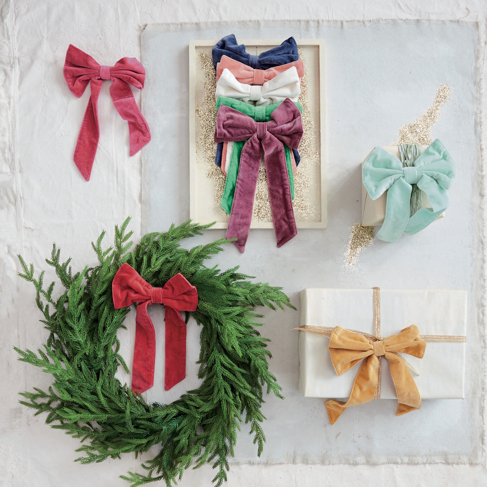 Various colored velvet bows displayed on a wreath, wrapped gifts, and a framed arrangement.