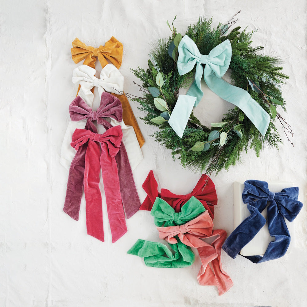Various colorful velvet bows arranged alongside a green holiday wreath.
