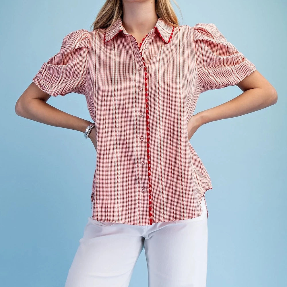 Woman wearing a red and white gingham button-down shirt with puffed sleeves, ric-rac trim, and red embroidery.
