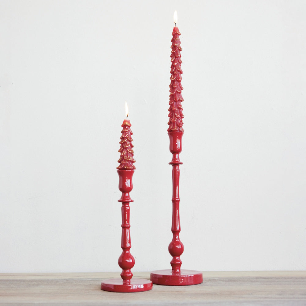 Two red taper candle holders with lit red decorative tree candles.