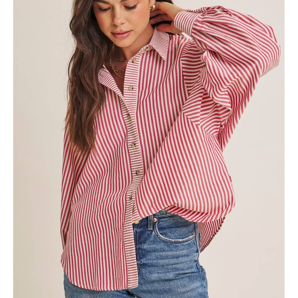 Woman wearing a red and white striped long-sleeve button-down shirt with batwing sleeves and blue jeans.
