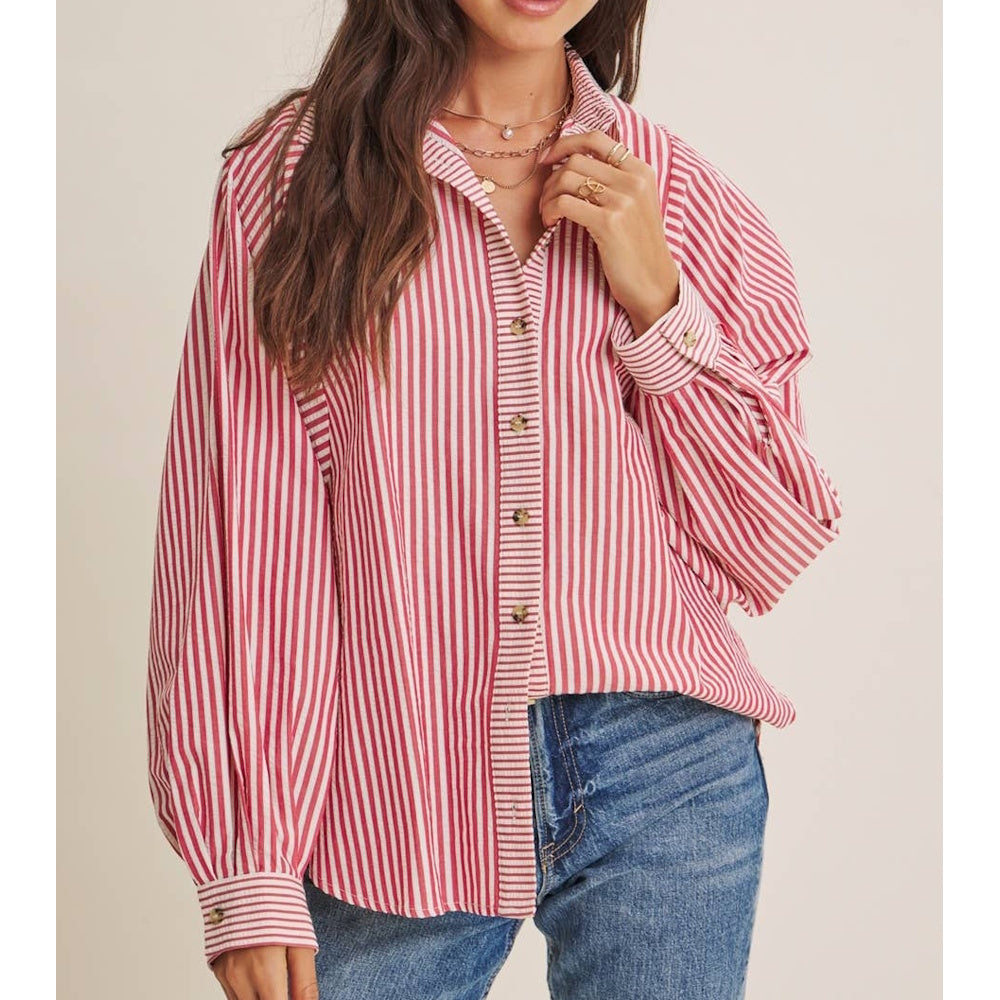 Woman wearing a relaxed-fit red and white vertical-striped button-down shirt tucked into blue jeans.
