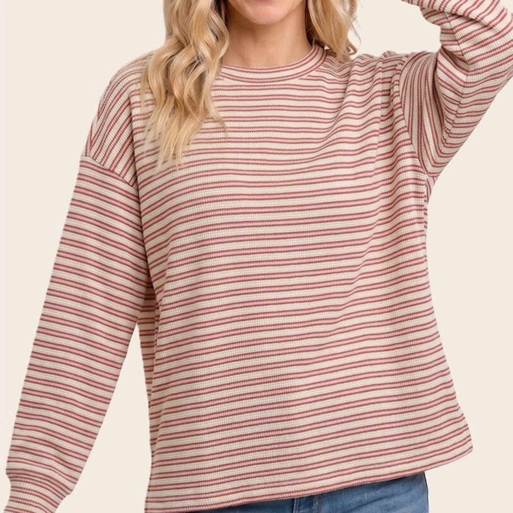 Woman wearing a long-sleeve waffle knit top with red horizontal stripes and crew neckline.