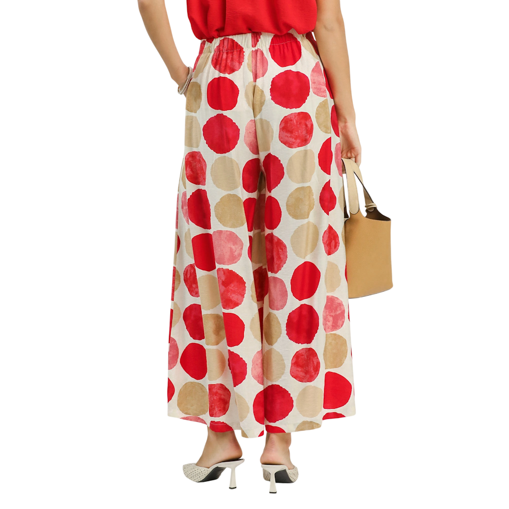 Person from behind wearing wide-leg white pants with large red and tan polka dots and a red top.