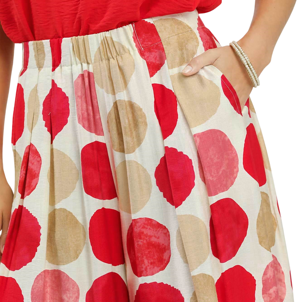 Close-up of a person wearing a cream skirt with large red and tan polka dots and a red top.