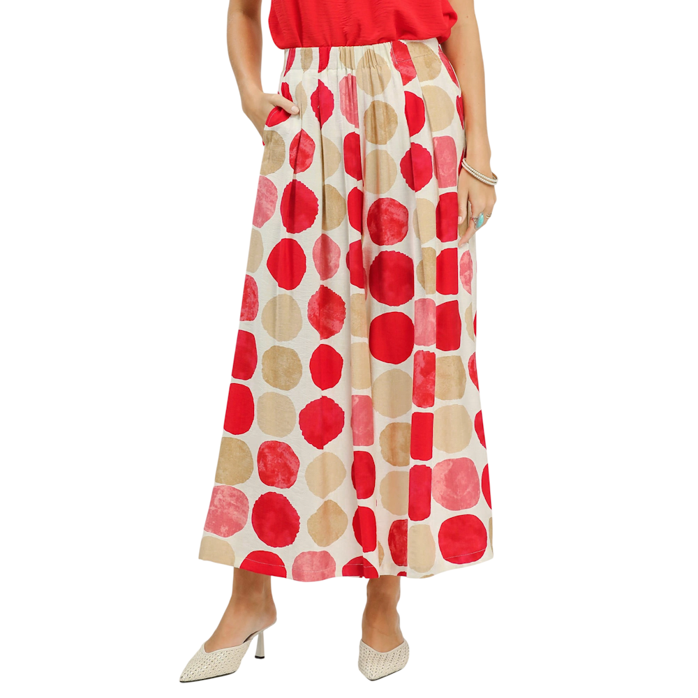 A person wearing wide-leg trousers with a large red, pink, and tan polka dot pattern and pointed-toe heels.
