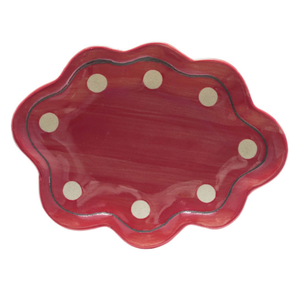Red stoneware scalloped dish with white polka dots and a dark border on a white background.