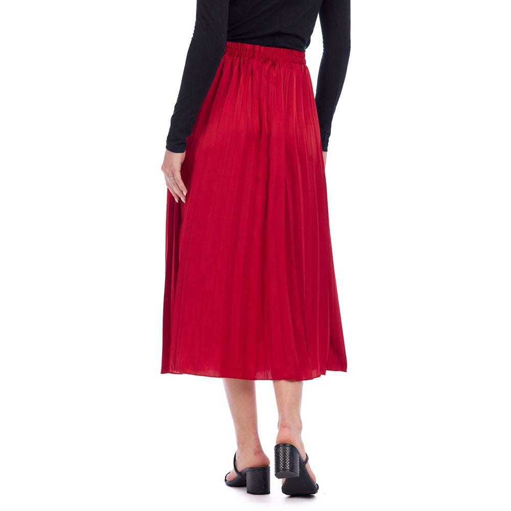 A red, midi-length pleated Townes skirt with an elastic waistband, styled with a black top and block-heeled sandals.