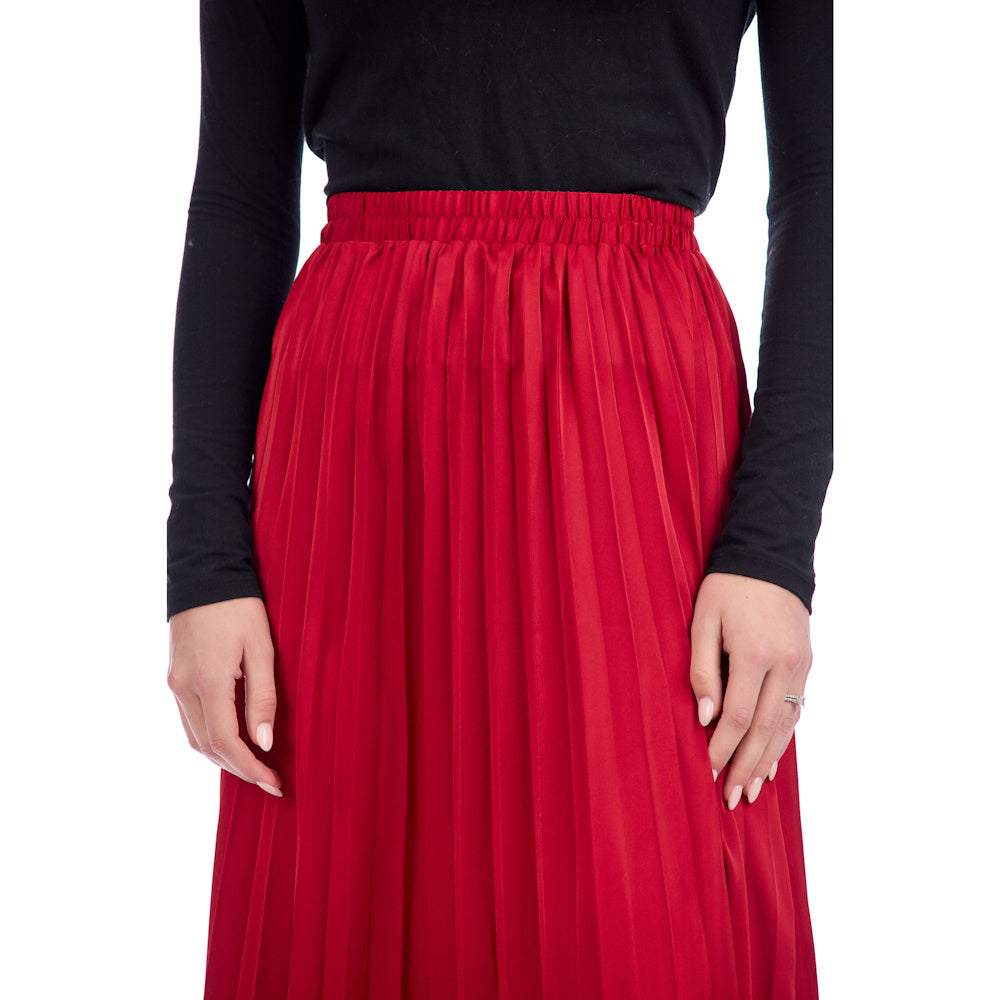 A woman wearing a vibrant red pleated Townes midi skirt with an elastic waistband and a long-sleeve black top.