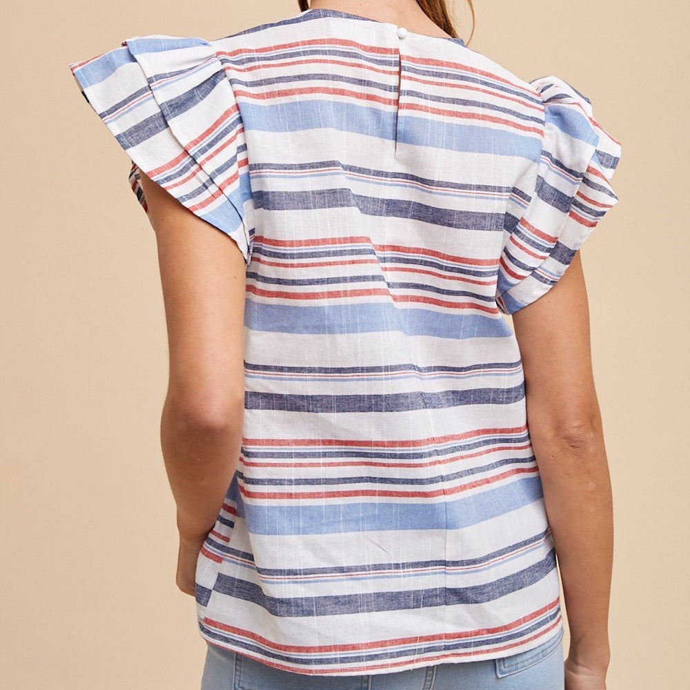 A rear view of a woman wearing a red, white, and blue horizontally striped top with ruffled cap sleeves.