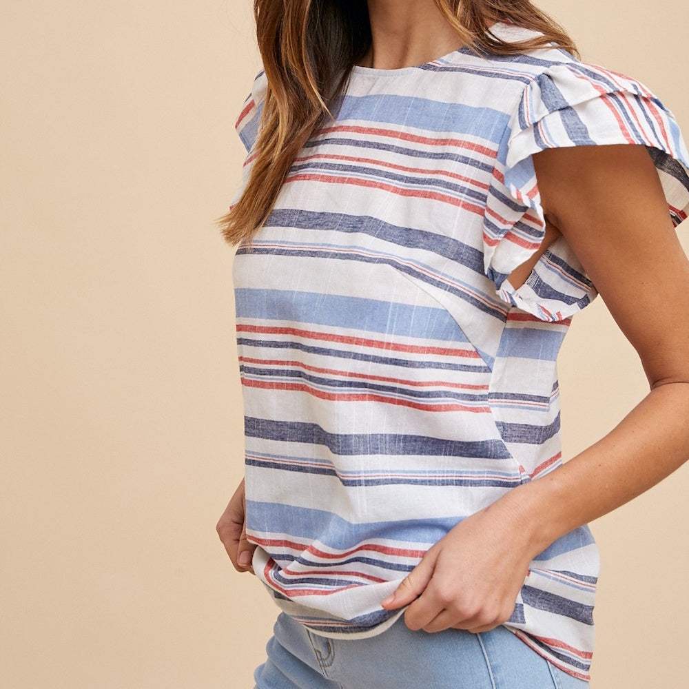 A woman wearing a red, white, and blue striped top with ruffled cap sleeves and light blue jeans.