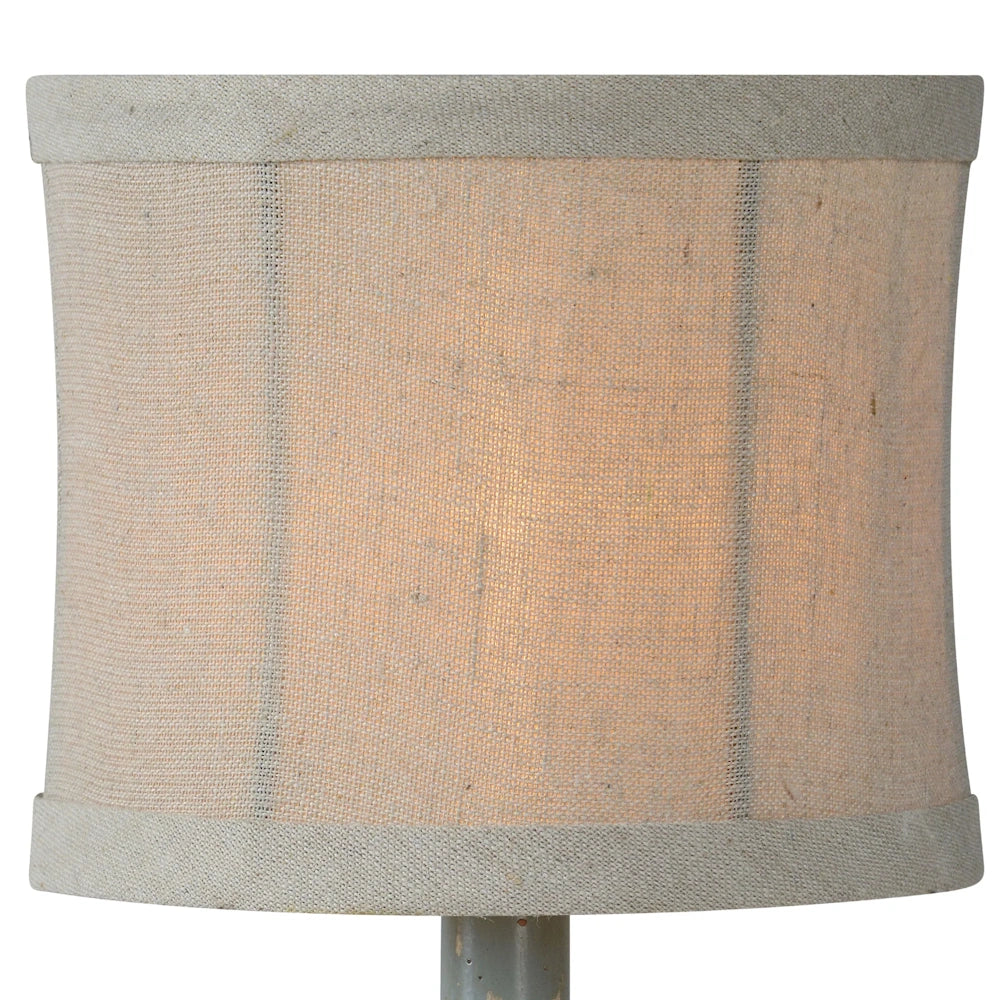 Close-up of a neutral linen drum lampshade with a subtle vertical stripe pattern on a rustic table lamp.