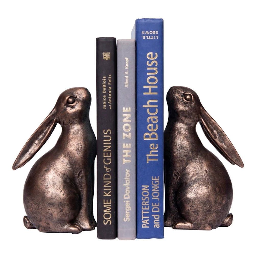 Bronze resin rabbit bookends holding three hardcover books on a plain white background.