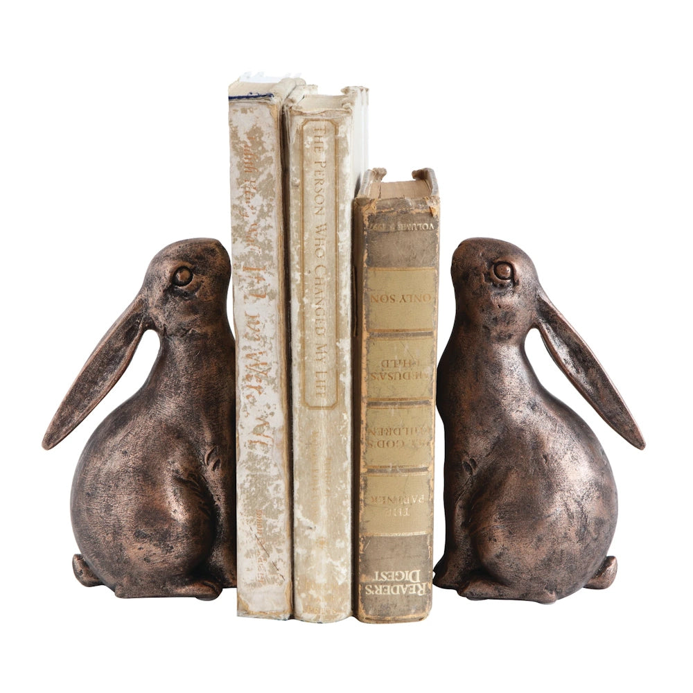 Bronze-finished resin rabbit bookends holding a row of vintage books on a white background.