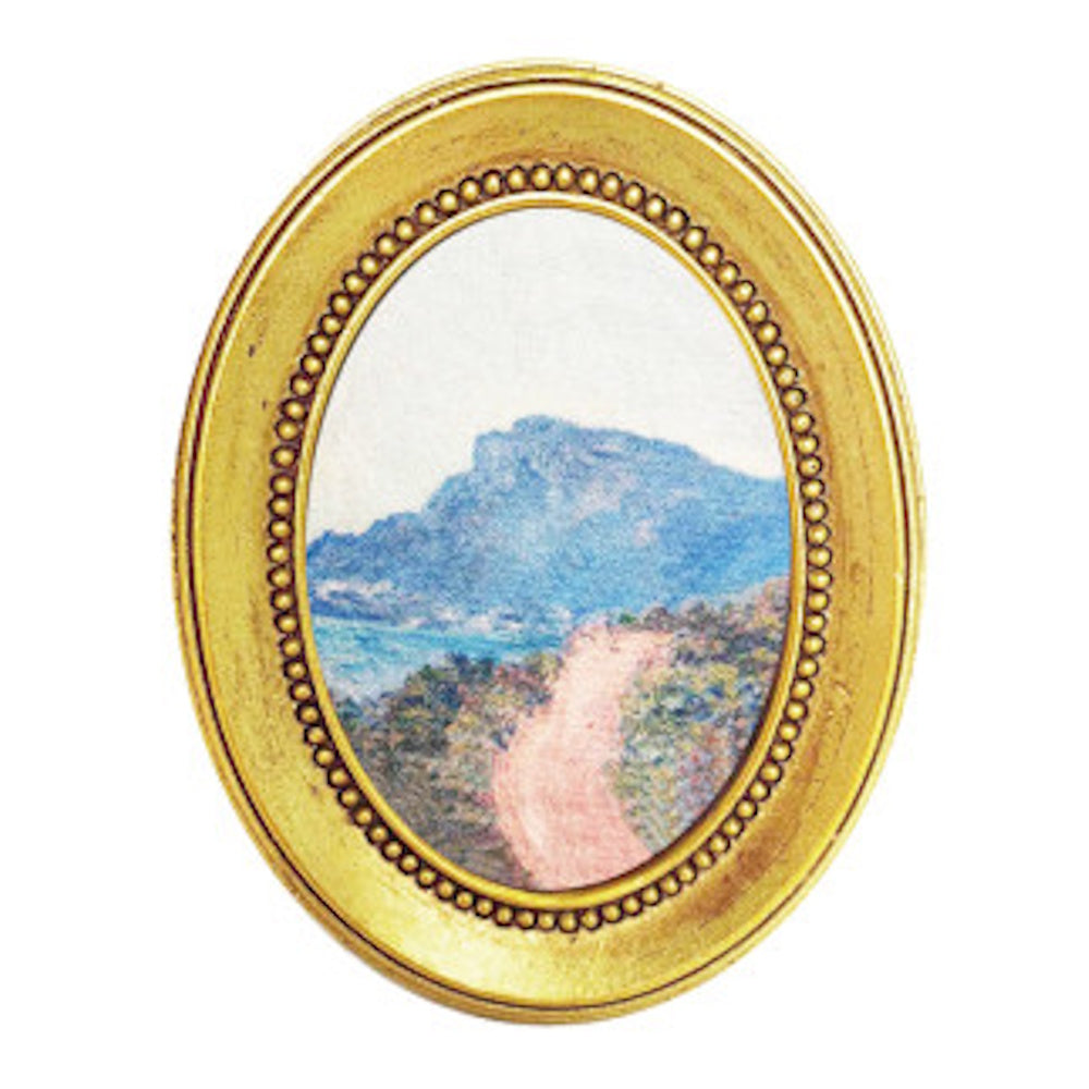 Impressionist landscape painting of a mountain and path in an ornate gold oval frame on white background.