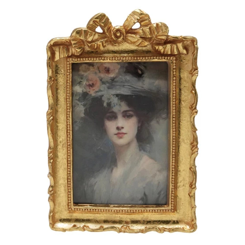 Vintage gold resin photo frame with a decorative bow and beaded trim, featuring a classic portrait of a woman.