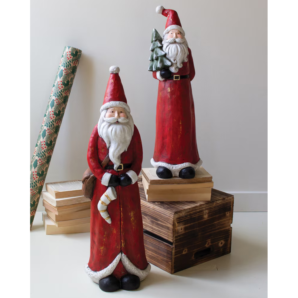Two tall resin Santa figurines standing on books and a wooden crate.
