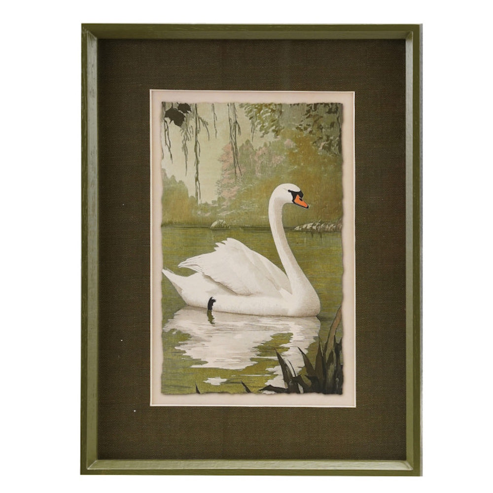 Framed artwork of a white swan swimming on a pond, surrounded by a dark green mat and wood frame.