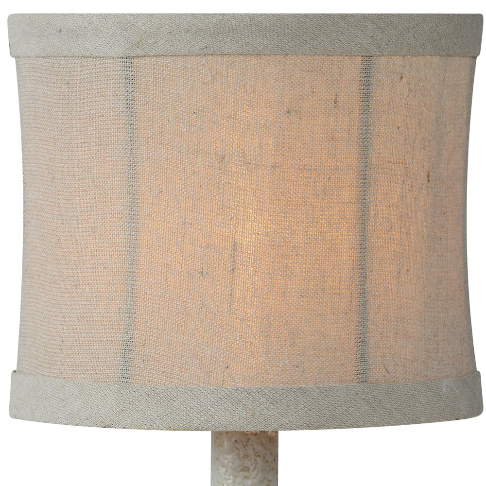 Close-up of a neutral linen drum lamp shade with subtle vertical stripes and a warm interior glow.