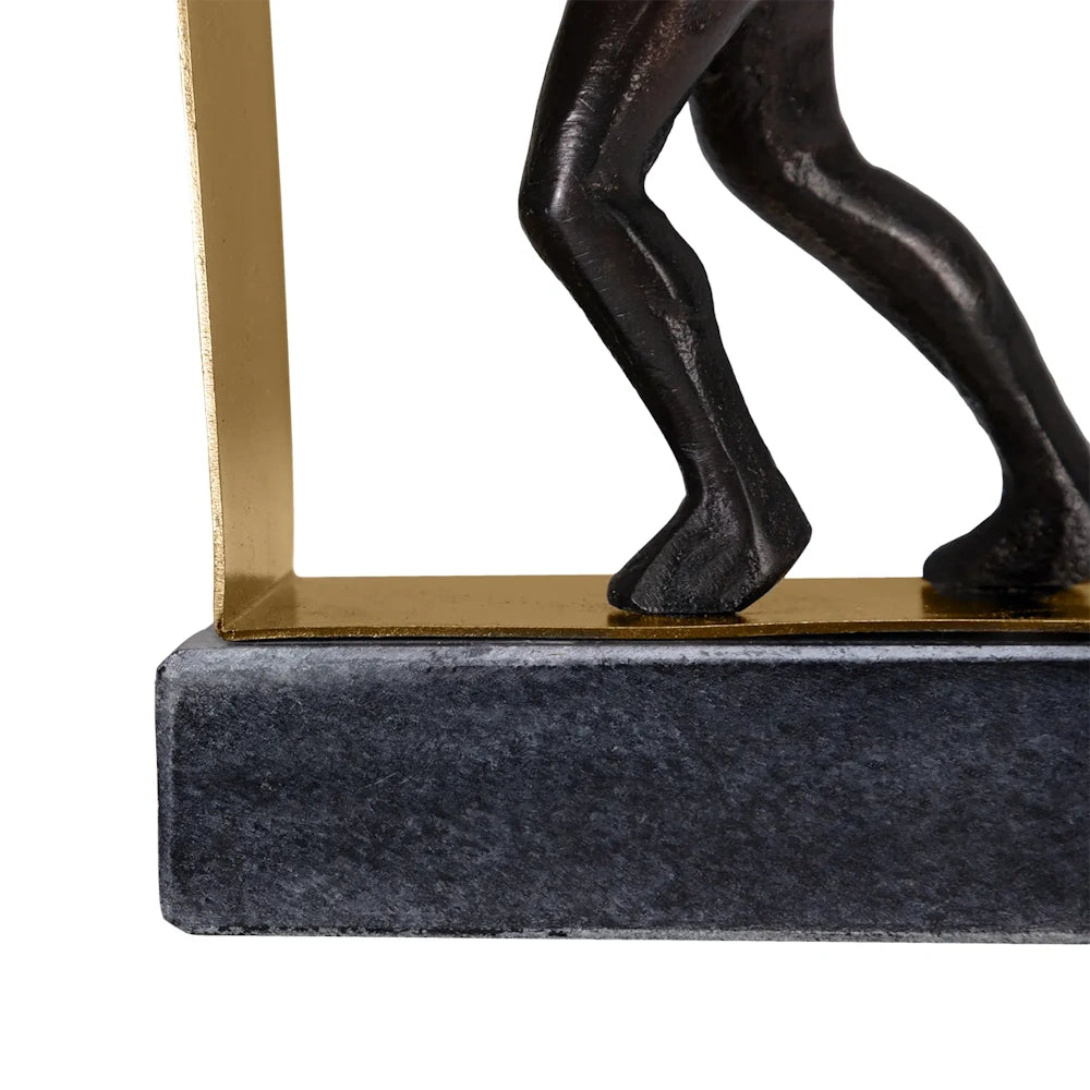 Close-up of a bronze sculpture's legs on a gold-toned L-shaped metal bracket attached to a dark marble base.
