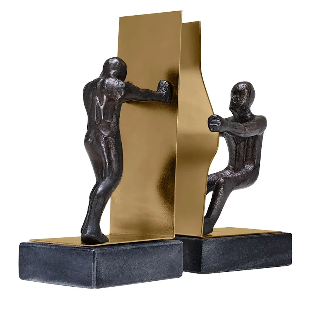 Side angle of two bronze figure bookends, one pushing a flat gold panel and one pulling a curved gold panel.