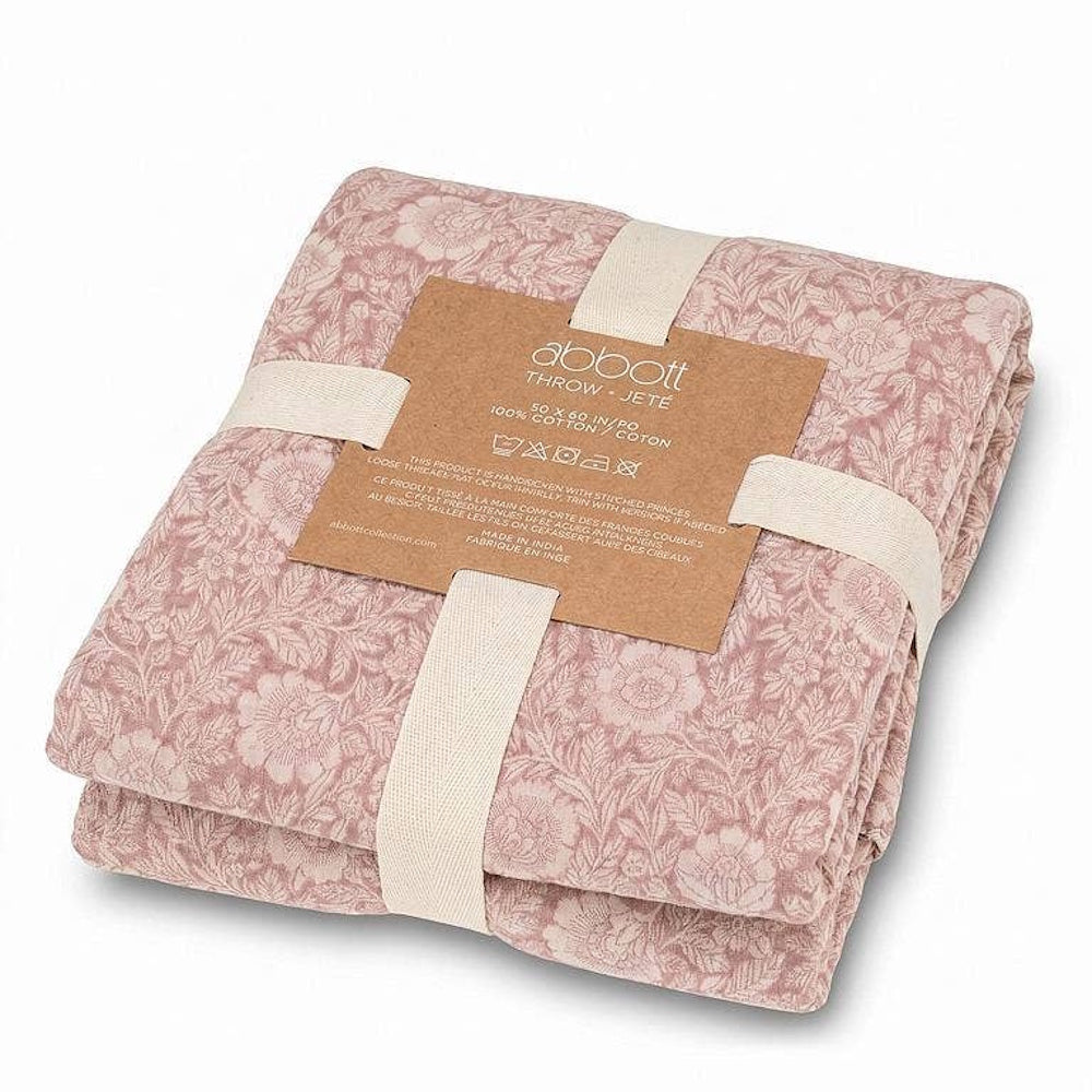 Folded pink floral jacquard throw blanket neatly wrapped in a white ribbon with product label.