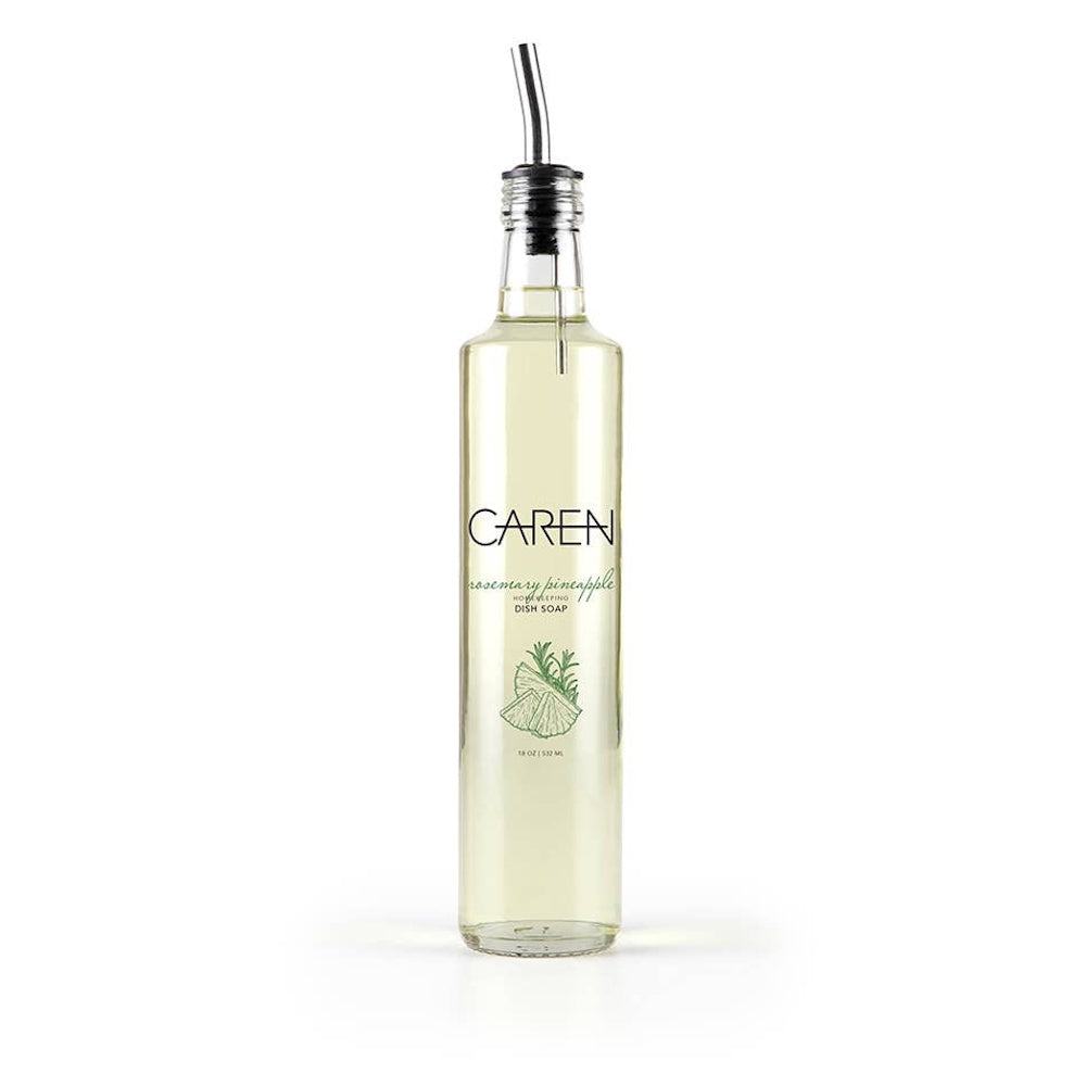 A clear glass bottle of Caren Rosemary Pineapple dish soap with a silver pour spout on a white background.