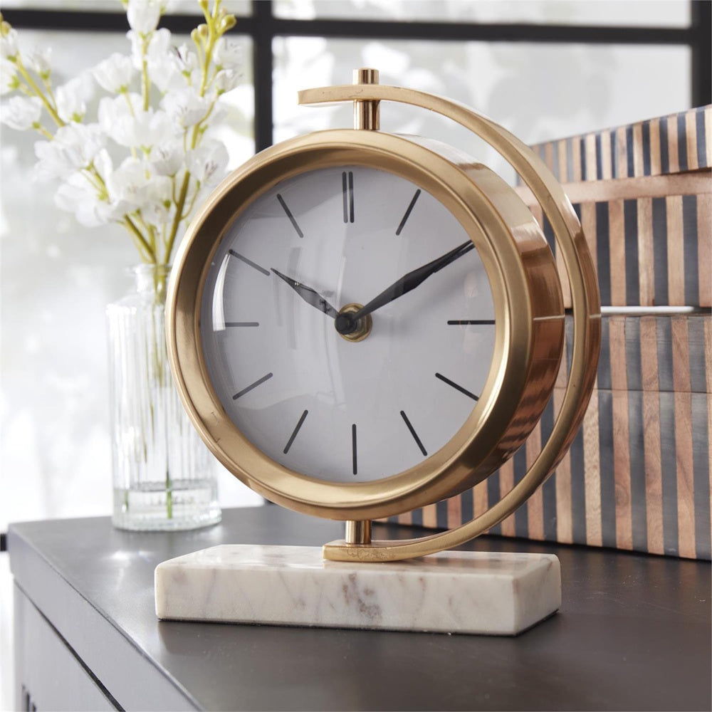 Modern round gold mantel clock on a white marble base with a sleek minimalist face and black hands.