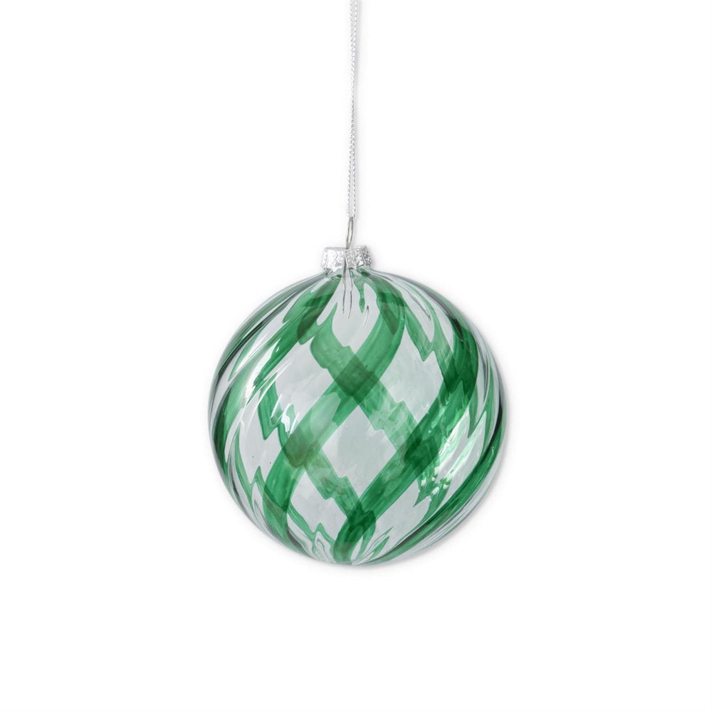 A hanging round green and clear glass ornament featuring swirled patterns.