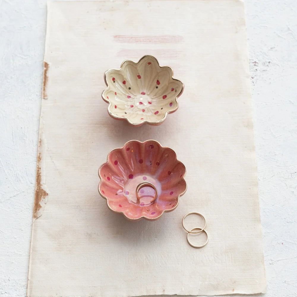 Two fluted stoneware trinket dishes in pink and cream with gold rims and red polka dots, styled with gold rings.