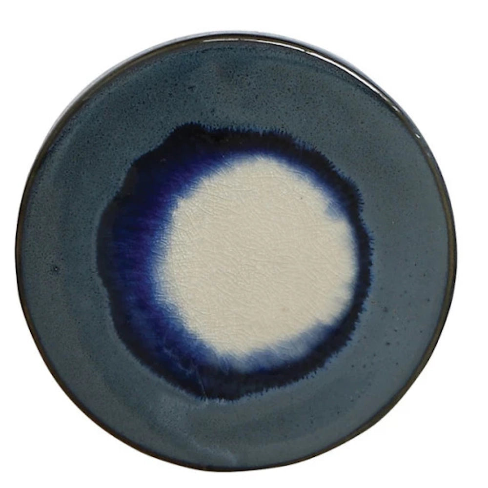 A handmade blue ceramic plate with an unglazed white center and crackle finish, ideal for modern rustic dining.